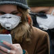 People wearing protective face masks use a smartphone